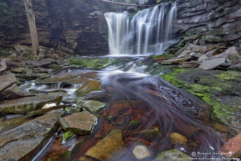 Beams of light illuminate a portion of the cascade and moss covered rocks at Elakala Falls in Blackwater Falls State Park, WV.